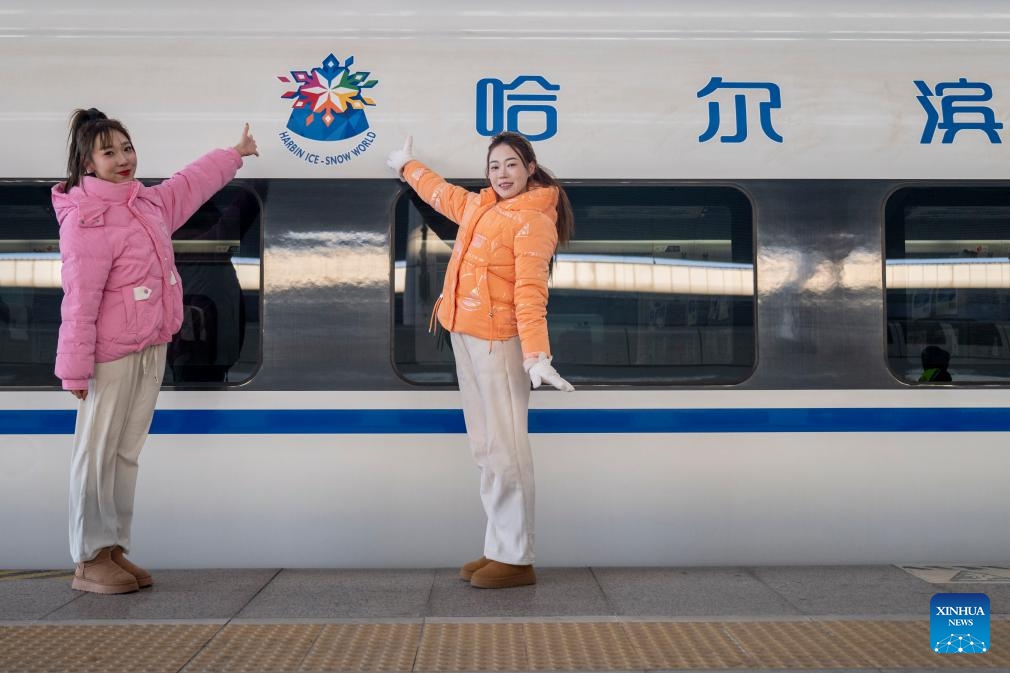 Performers pose for a photo in front of the bullet train No.G1276, the first themed high-speed train of the Harbin Ice-Snow World, at Harbin West Station in Harbin, northeast China's Heilongjiang Province, Jan. 4, 2026. The first high-speed train with the theme of the Harbin Ice-Snow World began service from Harbin West Station on Sunday, heading for Wuhan City in central China's Hubei Province. Featuring unique interior and exterior decorations of the Harbin Ice-Snow World, the themed high-speed train serves as a mobile emblem to boost the ice and snow economy. (Photo: Xinhua)