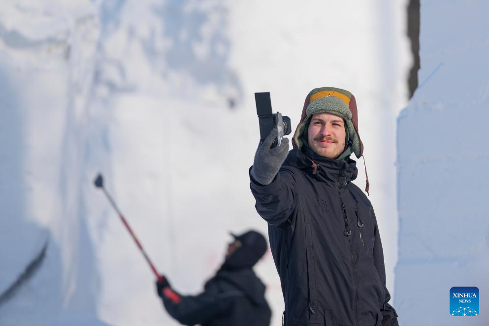 A contestant takes photos at the compound for the Sun Island International Snow Sculpture Art Expo in Harbin, northeast China's Heilongjiang Province, Jan. 6, 2026. The 28th Harbin international snow sculpture competition kicked off here on Tuesday, attracting 25 teams of snow sculptors from 13 countries. (Xinhua/Wang Jianwei)