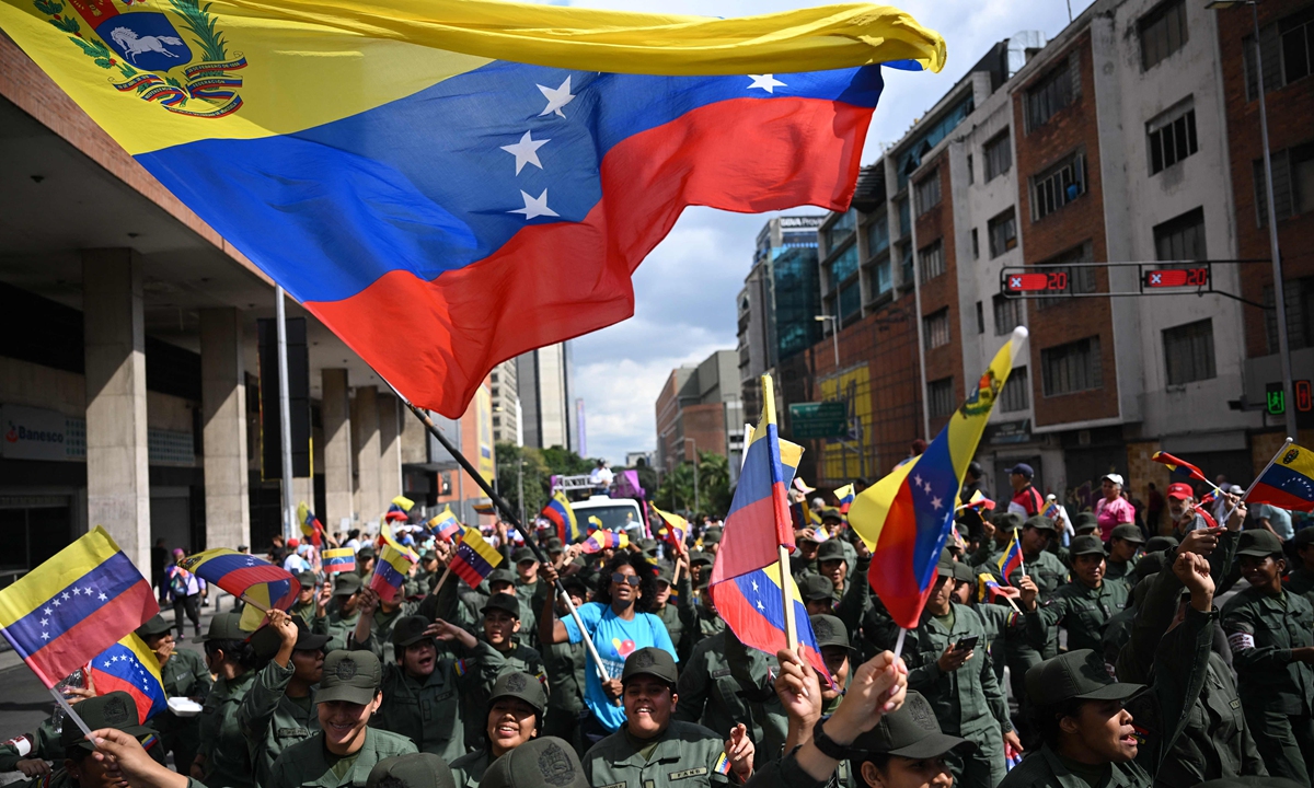 A woman waves a Venezuelan flag among members of the National Bolivarian Armed Forces during a rally in support of ousted Venezuela's President Nicolas Maduro and his wife Cilia Flores in Caracas on January 6, 2026. Photo: VCG