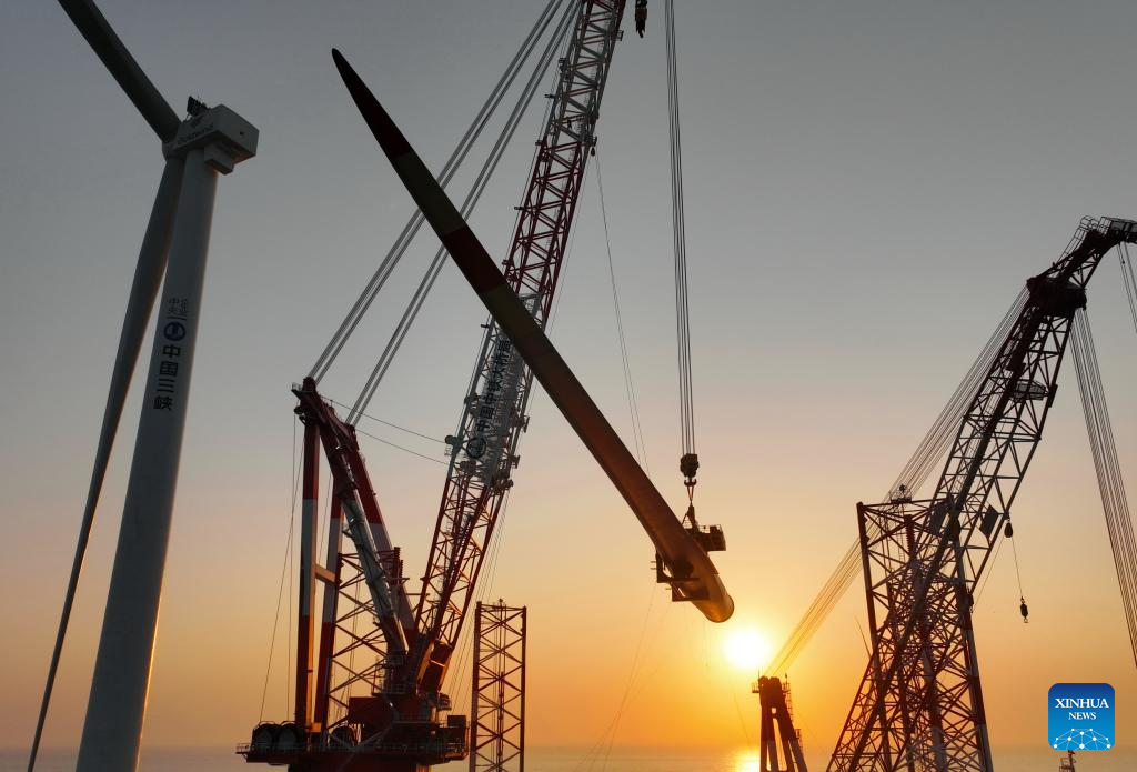 This drone photo taken on Jan. 13, 2026 shows one of the turbine blades being hoisted at the construction site of a 20-megawatt offshore wind turbine unit in the coastal waters of southeast China's Fujian Province. The wind turbine unit was successfully hoisted and installed here on Tuesday. (Xinhua/Lin Shanchuan)