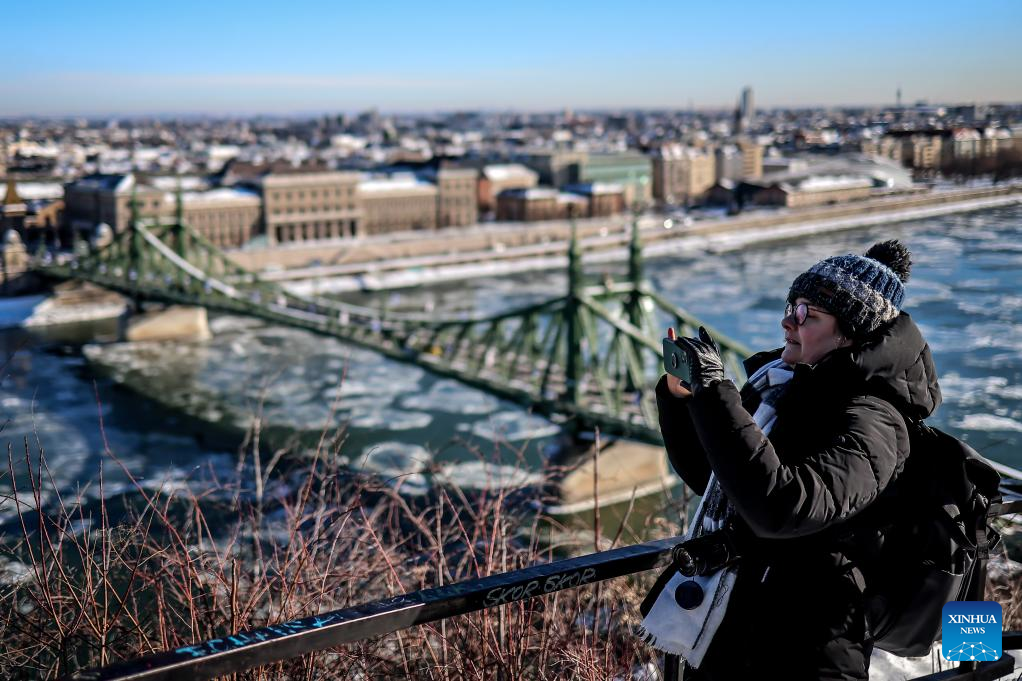 A woman takes photos of the Danube River with drifting ice floes in Budapest, Hungary, on Jan. 12, 2026. (Photo by David Balogh/Xinhua)