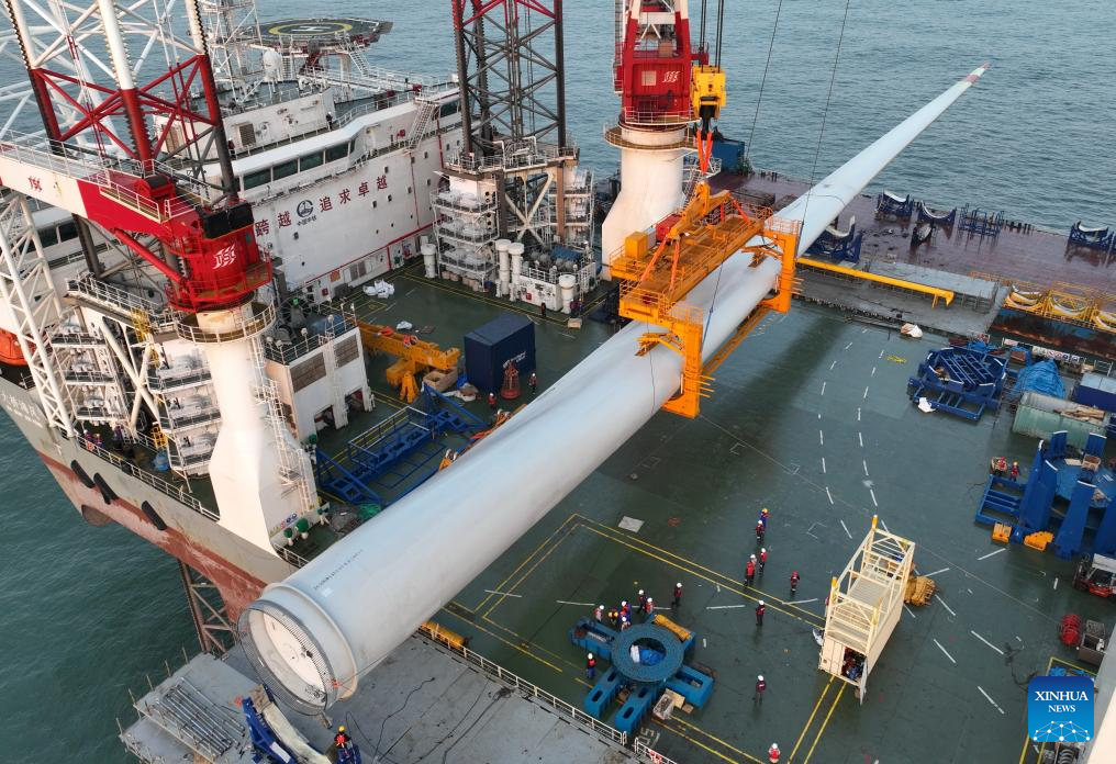 This drone photo taken on Jan. 13, 2026 shows one of the turbine blades being hoisted at the construction site of a 20-megawatt offshore wind turbine unit in the coastal waters of southeast China's Fujian Province. The wind turbine unit was successfully hoisted and installed here on Tuesday. (Xinhua/Lin Shanchuan)