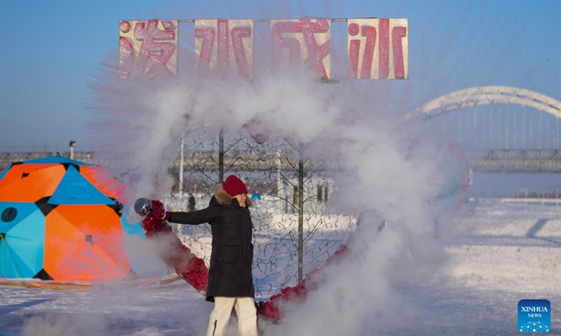 A tourist plays a water to ice stunt by splashing water into the cold air on the frozen surface of the Songhua River in Harbin, northeast China's Heilongjiang Province, Jan. 10, 2026. The surface of the Harbin section of Songhua River, now solidly frozen, serves as a fun field, where locals and tourists alike enjoy themselves with ice-and-snow-themed amusements. (Xinhua/Wang Jianwei)