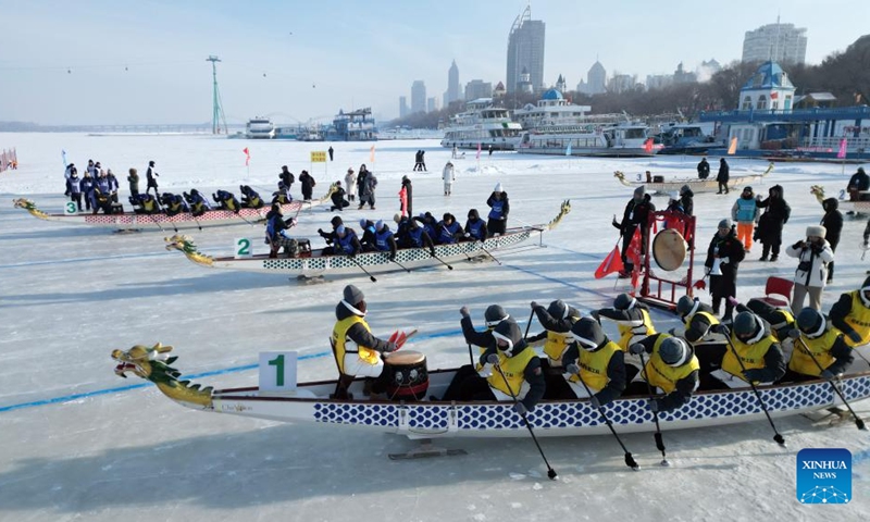 A drone photo taken on Jan. 9, 2026 shows people participating in a dragon boat competition on the frozen surface of the Songhua River in Harbin, northeast China's Heilongjiang Province. The surface of the Harbin section of Songhua River, now solidly frozen, serves as a fun field, where locals and tourists alike enjoy themselves with ice-and-snow-themed amusements. (Photo by Liu Yang/Xinhua)