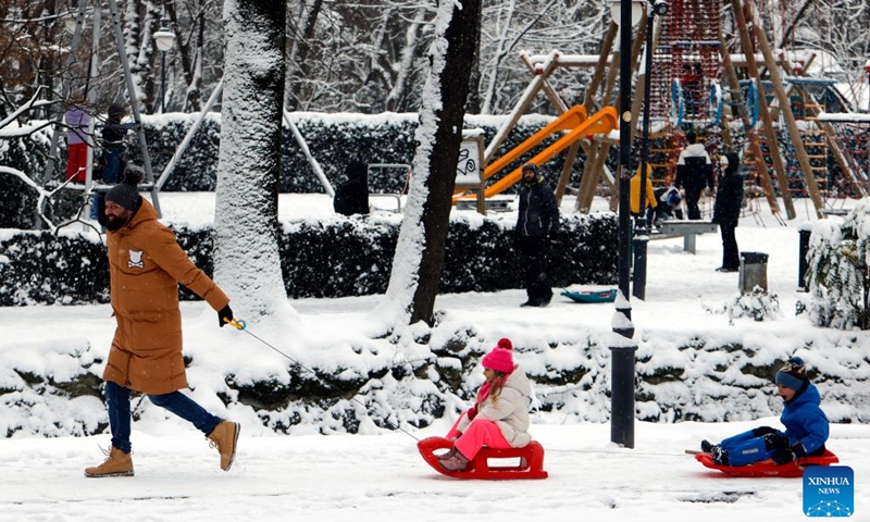 A man pulls two sledges carrying his children amid snowfall at a park in Bucharest, Romania, on Jan. 11, 2026. Romania is facing a severe winter episode, with snowfall, blizzards, persistent frost and extremely low temperatures in large parts of the country. Photo: Xinhua