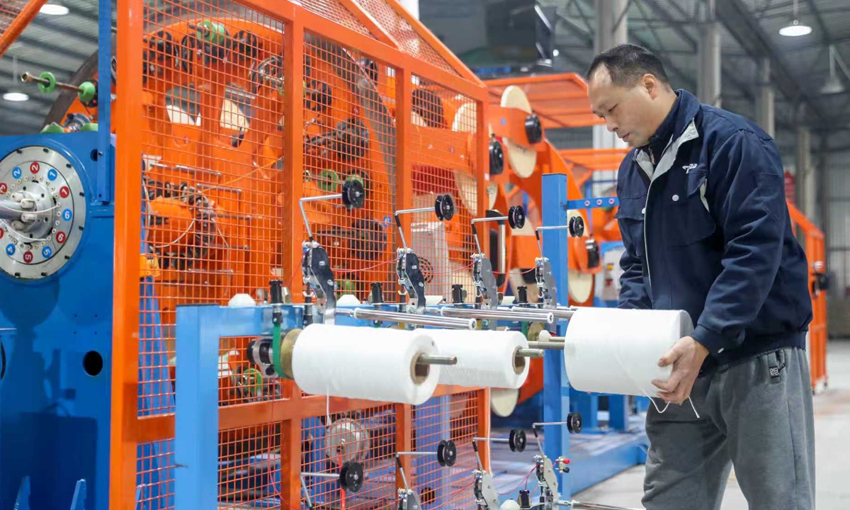 A worker at a wire and cable manufacturer in Huaying, Southwest China's Sichuan Province, prepares raw materials for producing ultra-flexible cables after assigning production orders to smart equipment at an 