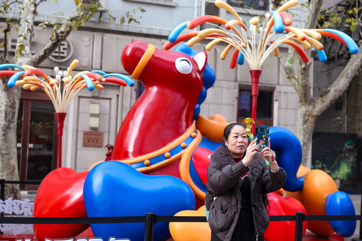 A woman takes a selfie in front of a horse sculpture with a golden ingot on its back in Shanghai on January 13, 2026. To celebrate the upcoming Year of the Horse, the sculpture is named Mashang Youqian, meaning both 