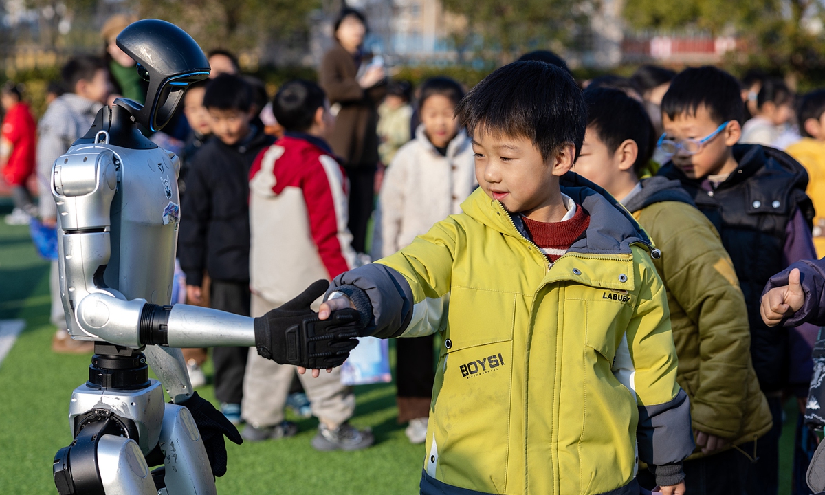A primary school student in Huzhou, East China's Zhejiang Province, shakes hands with a robot during a final exam on January 15, 2026. The exam assessed students' comprehensive literacy and practical application skills. Photo: VCG