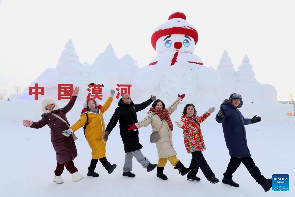 Tourists pose for photos in front of a giant snowman near the Mohe Railway Station in Mohe, northeast China's Heilongjiang Province, Jan. 16, 2026. With the arrival of the ice and snow season, various public facilities in Heilongjiang Province have created distinctive snowman-themed landscapes to attract locals and tourists. (Photo: Xinhua)