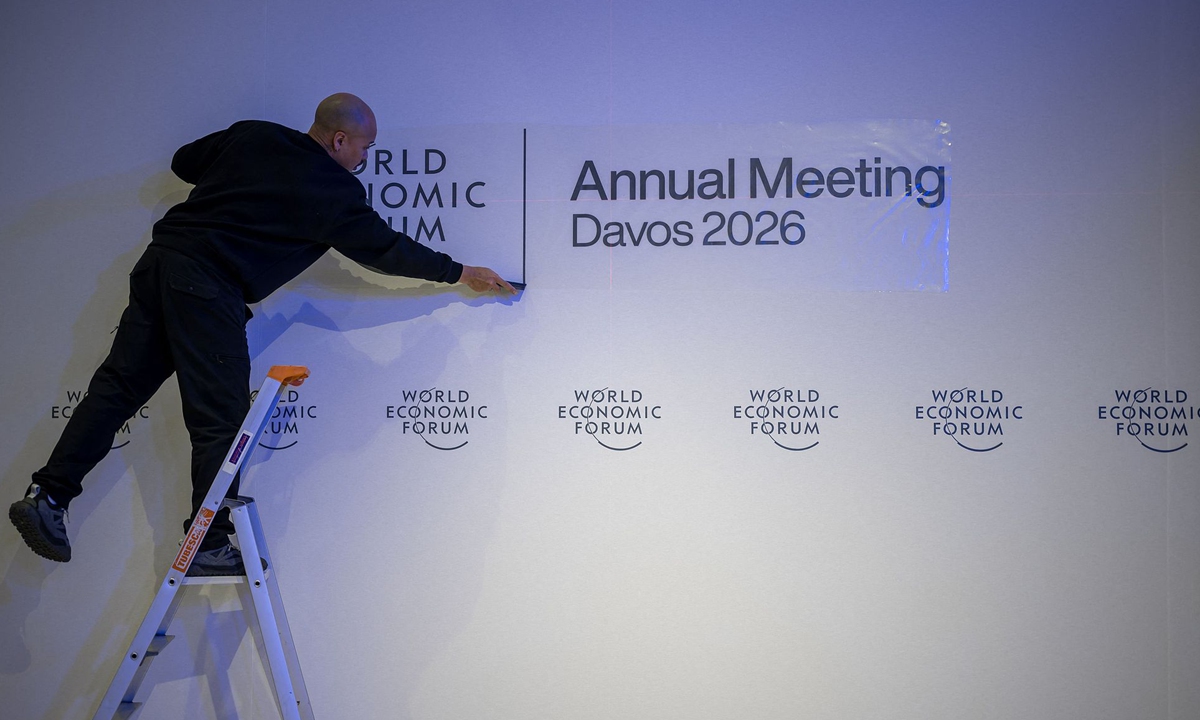 A staff member fixes a sign on a wall of the World Economic Forum at the Congress Center on its opening day in Davos on January 19, 2026. Photo: VCG