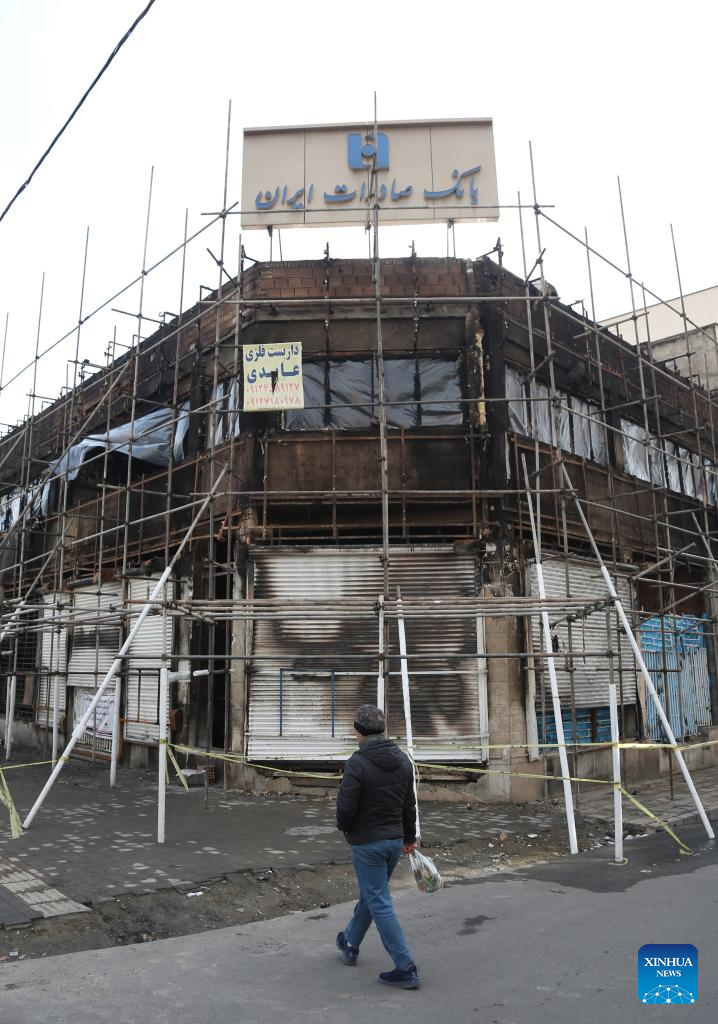 A pedestrian passes in front of a bank branch building damaged during the recent unrest in Tehran, Iran, Jan. 21, 2026. Iran's state television IRIB reported on Wednesday that 3,117 people were killed during recent unrest, citing the country's Forensic Medical Organization. (Xinhua/Shadati)