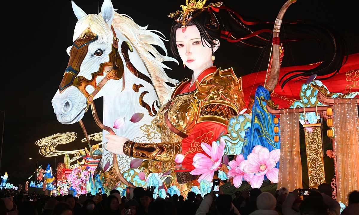 People walk past a huge lantern setting featuring Hua Mulan from Chinese legend at the 32nd Zigong International Dinosaur Lantern Festival in Zigong, Southwest China's Sichuan Province , on January 21, 2026. The festival held a preview lighting exhibition on this day, featuring 11 super-large lantern groups and more than 200 medium and small intangible cultural heritage lanterns, creating an immersive narrative space. Photo: VCG