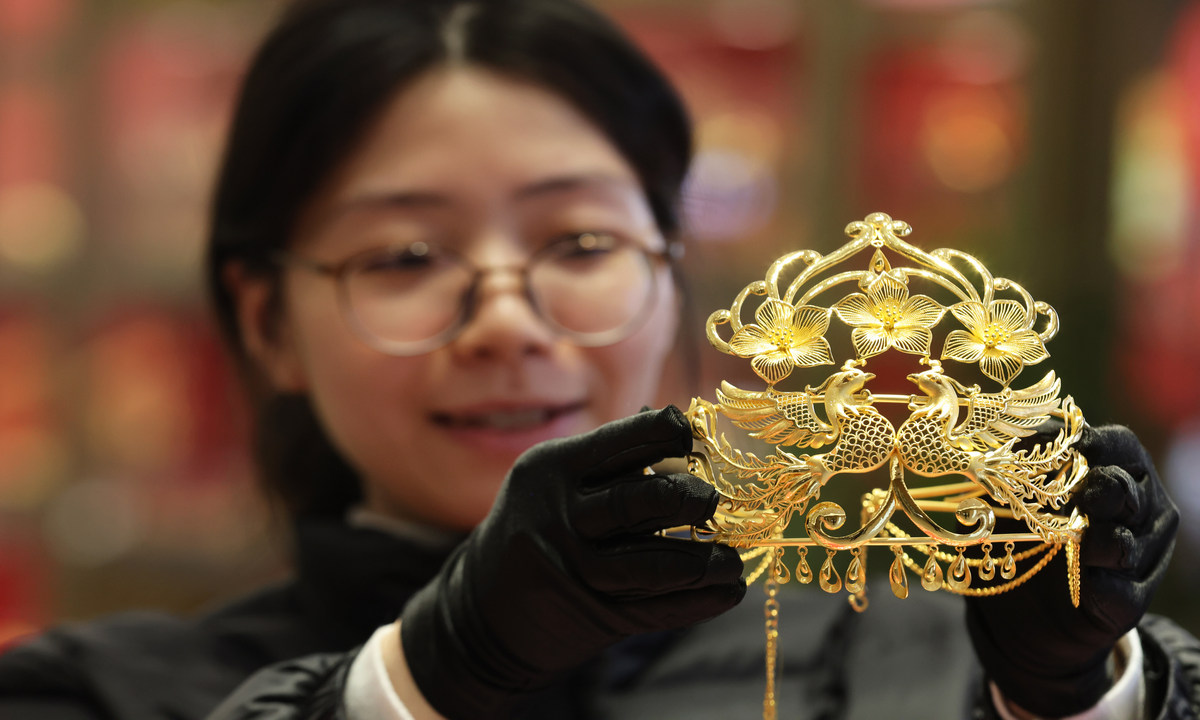 An employee displays gold ornaments at a shop in Hangzhou, East China's Zhejiang Province, on January 28, 2026. The approaching 2026 Spring Festival holiday has sparked a rush to buy gold among consumers despite global price rises. Photo: VCG