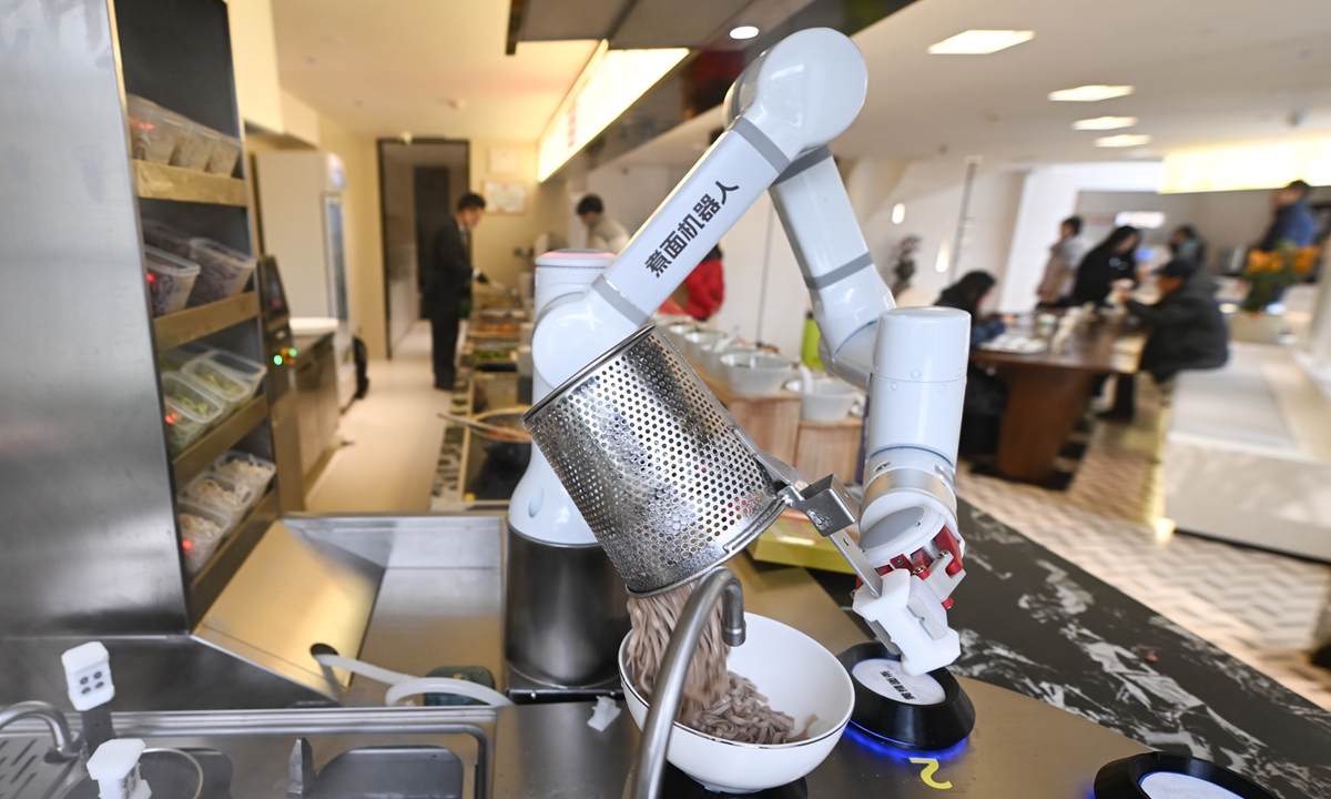 A robot pours cooked noodles into a bowl in a restaurant in Hangzhou, East China's Zhejiang Province on January 26, 2026. On that day, the restaurant officially opened, with robots transformed into chefs capable of cooking hundreds of dishes, attracting consumers to come and taste their creations. Photo: VCG