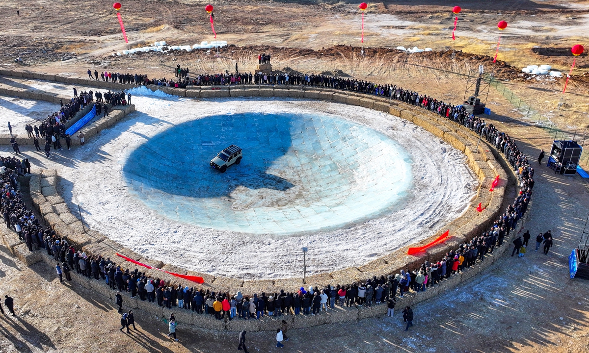 Spectators watch an off-road vehicle navigate a massive, bowl-shaped ice pit in Ulanqab, North China's Inner Mongolia Autonomous Region on January 28, 2026. The event drew hordes of tourists and professional drivers eager to experience the thrill and challenge this exciting winter sport. Crafted from ice bricks, the frozen 