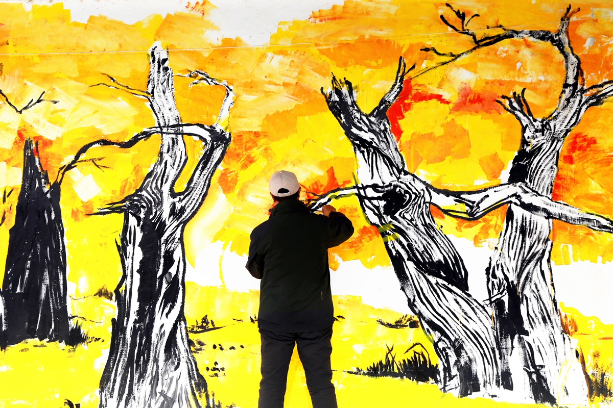 An artist draws a mural of desert poplars in Awati county, Northwest China's Xinjiang Uygur Autonomous Region, on January 29, 2026. Desert poplars can thrive in harsh conditions, withstanding cold, heat, alkali, and extreme drought while serving as a natural barrier against sandstorms. Photo: VCG