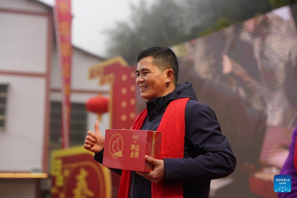 A villager displays a farm product on a festive gathering held during the Spring Festival gala in Shenshan Village, Jinggangshan City of east China's Jiangxi Province, Feb. 1, 2026. With the Spring Festival drawing near, Shenshan Village in Jinggangshan City held a Spring Festival gala that invited residents from seven nearby counties in east China's Jiangxi and central China's Hunan provinces to participate. (Xinhua/Zhou Mi)