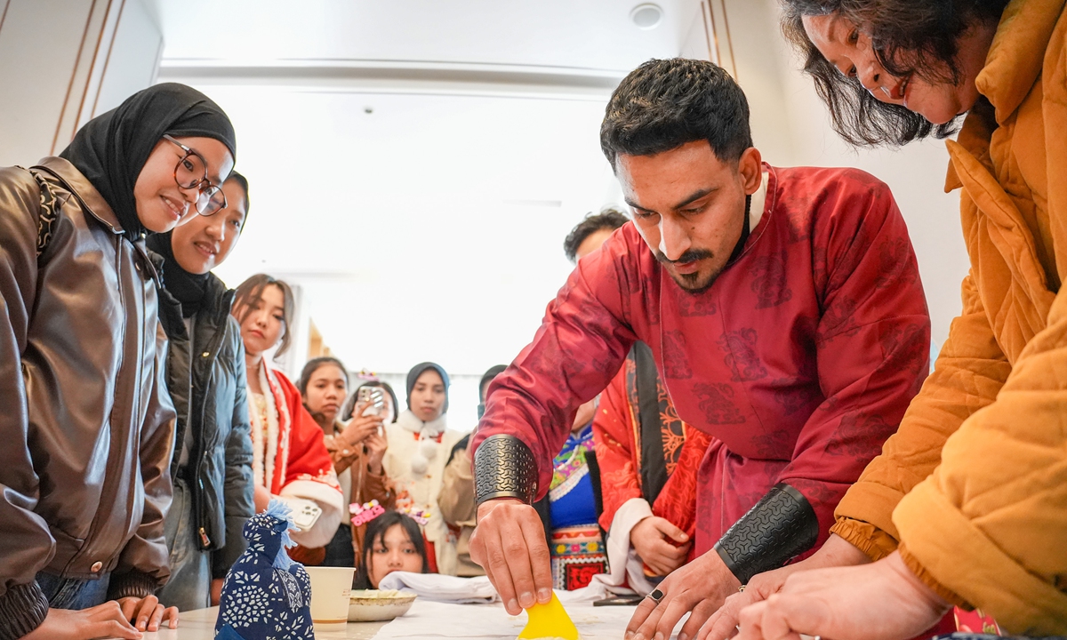 An international student (second from right) tries out Nantong blue calico printing at a Chinese New Year intangible cultural heritage folk customs event in Nantong, East China's Jiangsu Province, on February 4, 2026. Fifteen international students from countries such as Pakistan, Indonesia and Laos took part in the event, during which they also practiced writing Spring Festival couplets. Photo: VCG