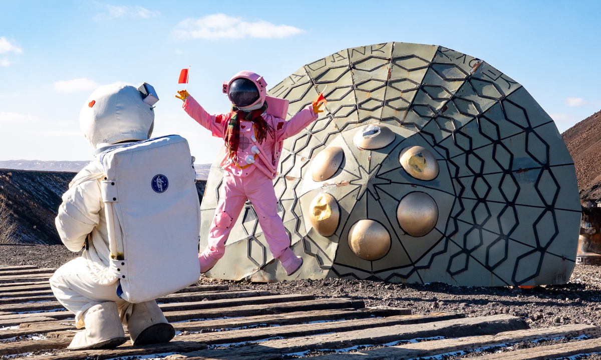 A tourist wearing a spacesuit takes a photo in front of the No.6 volcano at the Ulanhada volcano cluster geological park in North China's Inner Mongolia Autonomous Region on February 5, 2026. This volcano, thanks to its distinctive dark black and reddish-brown mountain massif, is hailed by visitors as a Mars base. Photo: VCG