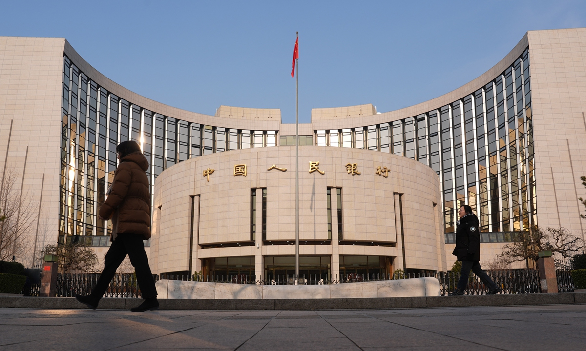 Two people go past the building of the People's Bank of China on December 22, 2025. Photo: VCG