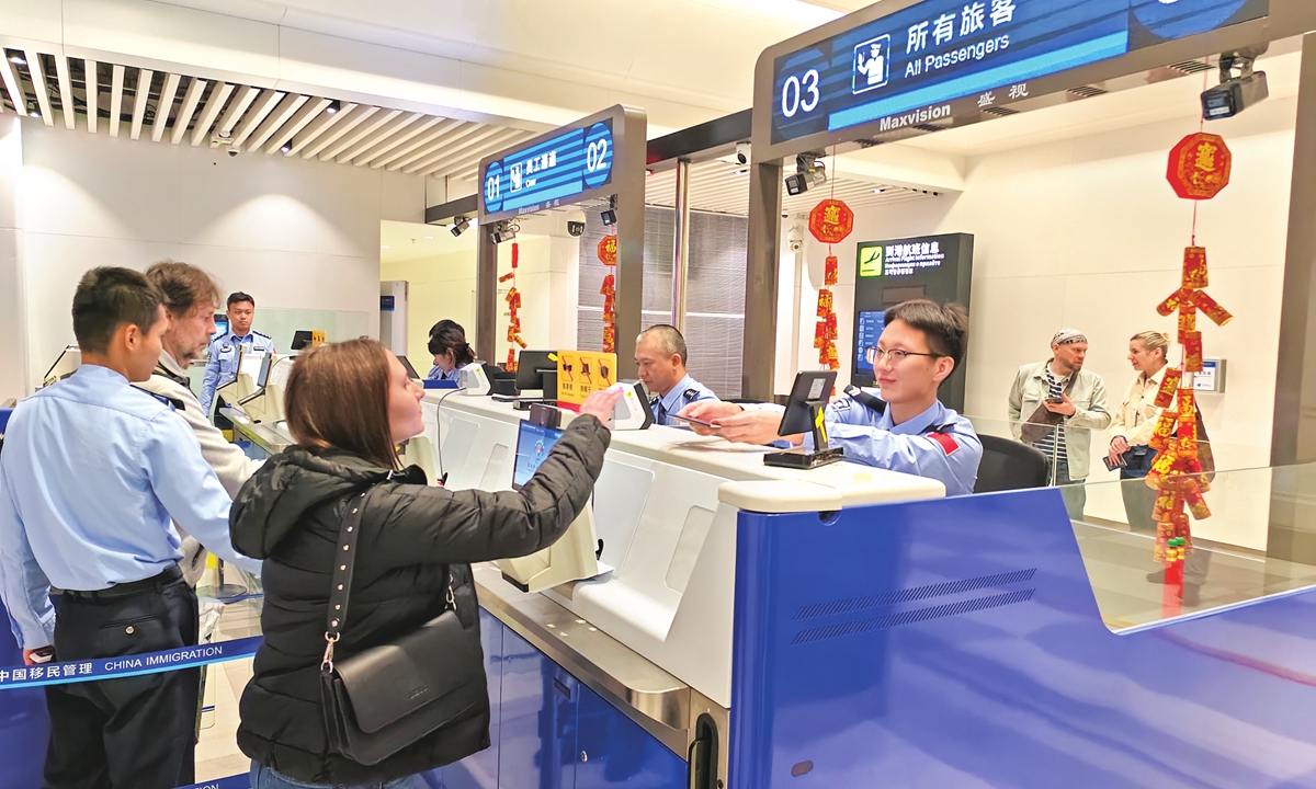 Wu Yuqi (third from right) of the Phoenix International Airport Station of Immigration Inspection hands the passport back to a foreign visitor at an inspection counter on February 5, 2026. Photo: Huang Lanlan/GT