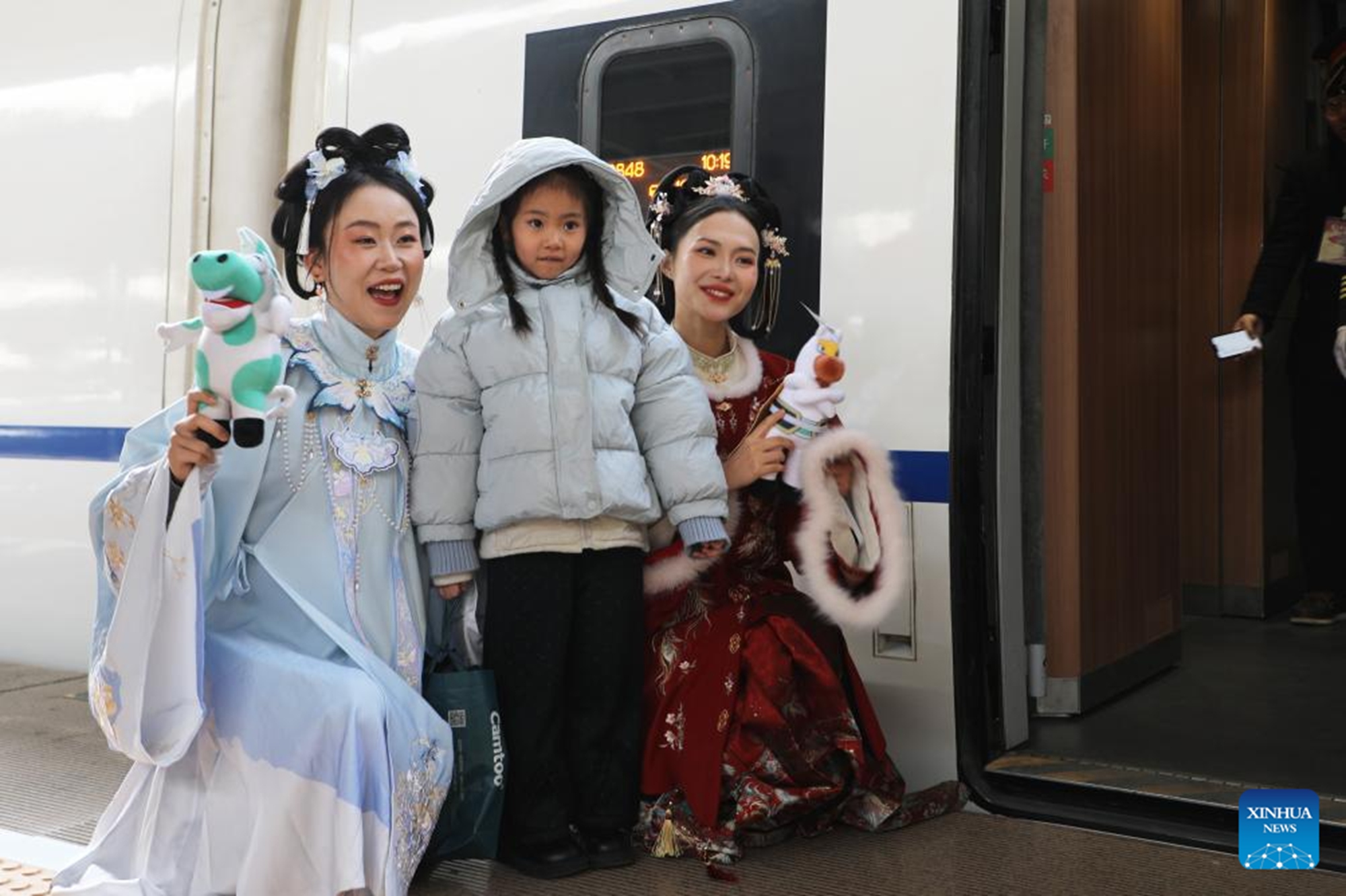 A tourist poses for photos with two costumed staff members of Wuwei Museum at Lanzhou West Railway Station in Lanzhou, northwest China's Gansu Province, Feb. 9, 2026. (Xinhua/Zhang Zhimin)

