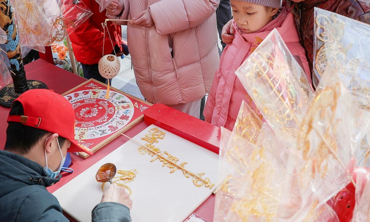 A child waits for a sugar painting at a Spring Festival market of Longfusi commercial area in Dongcheng District of Beijing, capital of China, on Feb. 10, 2026. As the Spring Festival approaches, the Longfusi commercial area is filled with festive atmosphere, attracting a large number of citizens and tourists to visit here. (Xinhua/Chang Nengjia)

