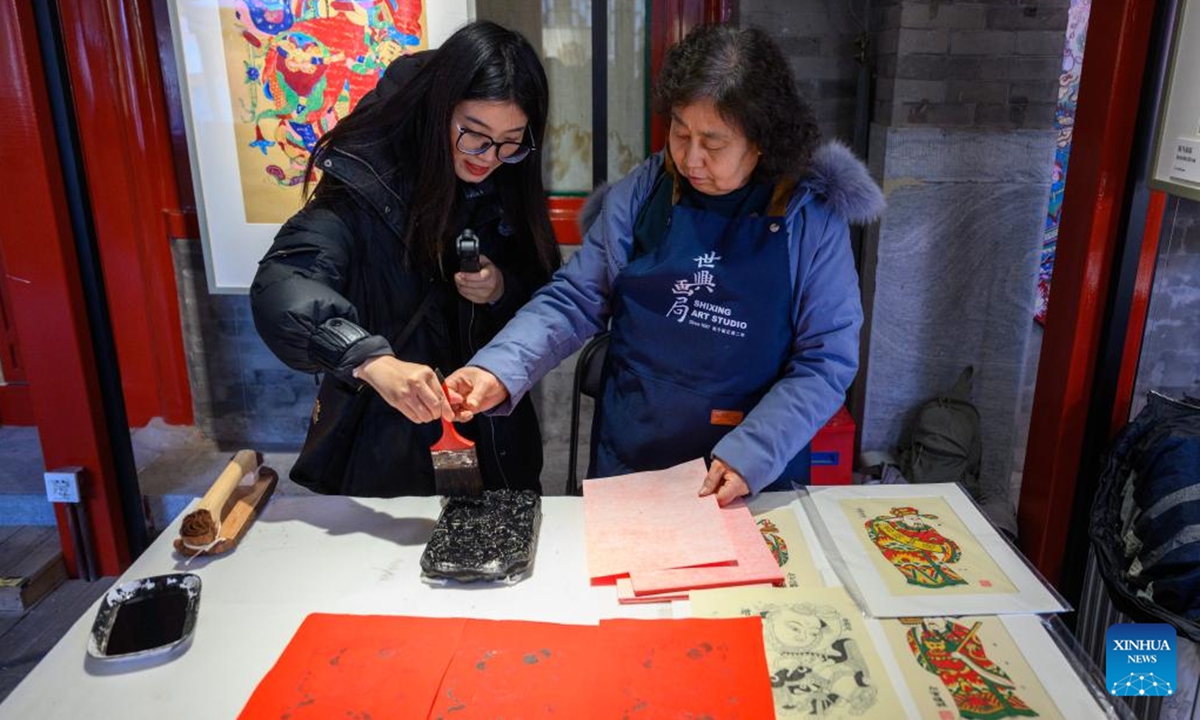 A tourist experiences the making of Chinese New Year paintings at Prince Kung's Palace Museum in Beijing, capital of China, Feb. 4, 2026. An exhibition displaying more than a hundred exquisite Chinese New Year paintings collected by Prince Kung's Palace Museum opened here on Wednesday. (Xinhua/Jin Liangkuai)

