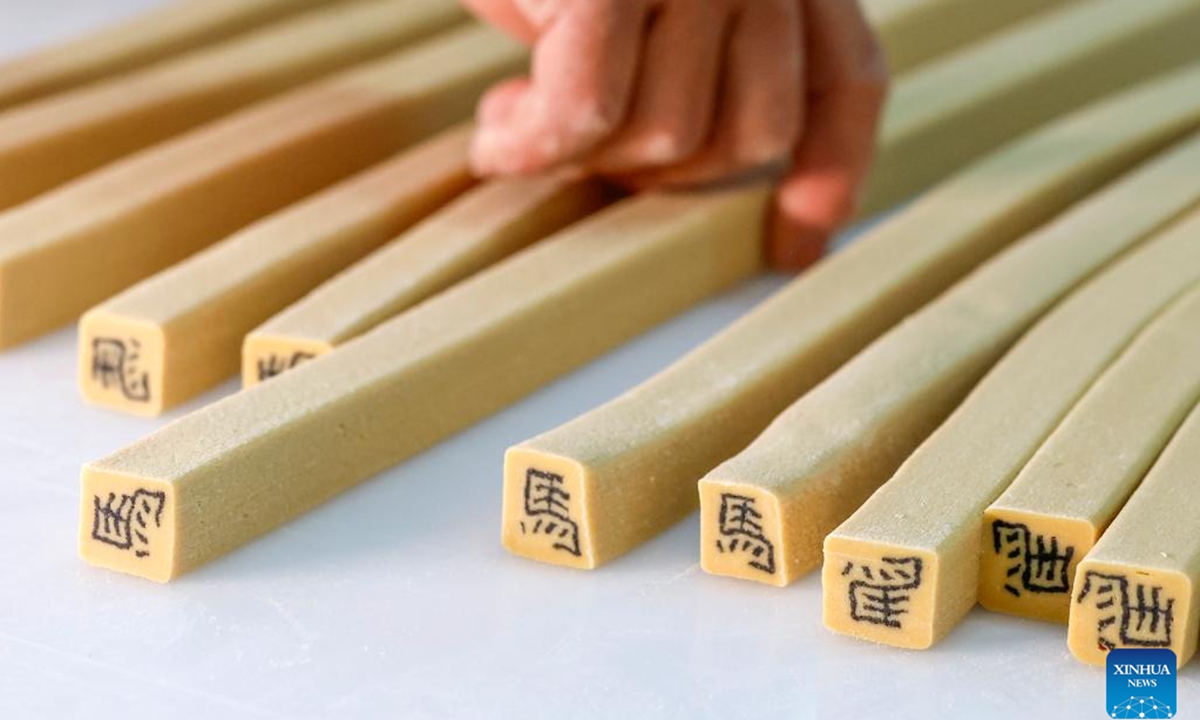 A staff member makes character-inlaid candies in Qimen County of Huangshan City, east China's Anhui Province, Jan. 13, 2026.