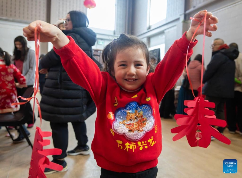 A girl poses for photos with her paper-cutting works in celebration of Chinese New Year at the Chinese Cultural Center of Greater Toronto in Toronto, Canada, Feb. 15, 2026. (Photo by Zou Zheng/Xinhua)