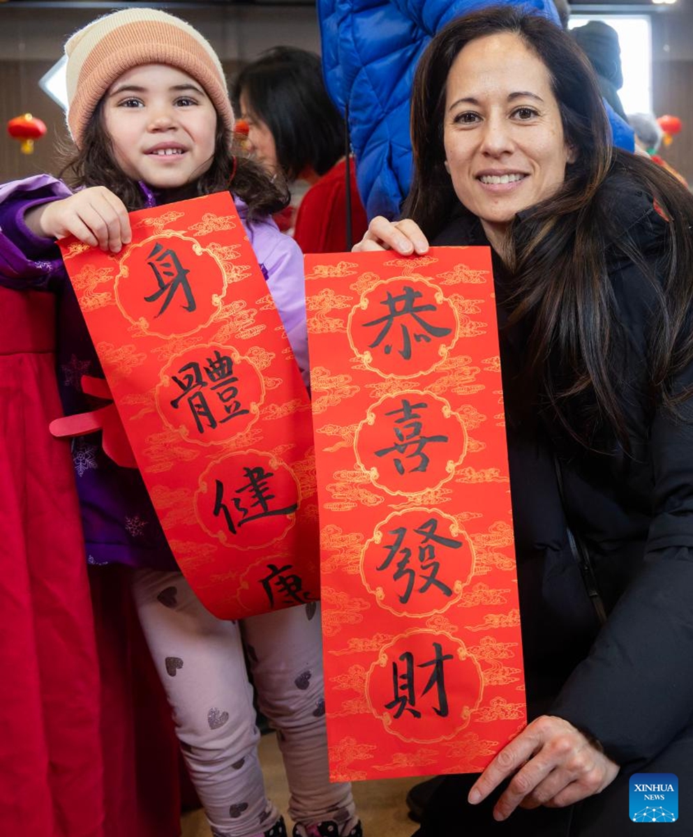 A woman and her child display Chinese calligraphy works in celebration of Chinese New Year at the Chinese Cultural Center of Greater Toronto in Toronto, Canada, Feb. 15, 2026. (Photo by Zou Zheng/Xinhua)