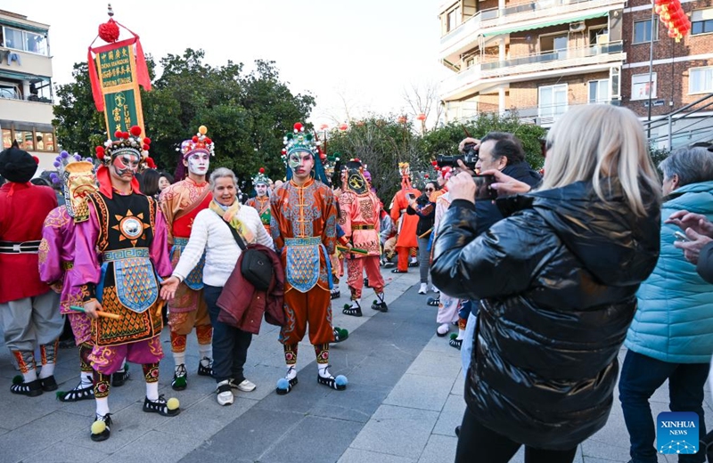 A woman poses for photos with Yingge dancers from Guangdong Jieyang during a Spring Festival temple fair event in Madrid, Spain, Feb. 20, 2026. (Photo by Gustavo Valiente/Xinhua)