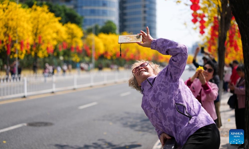 People take photos of tabebuia chrysantha blossoms in Guangzhou, south China's Guangdong Province, Feb. 20, 2026. (Xinhua/Wu Lu)