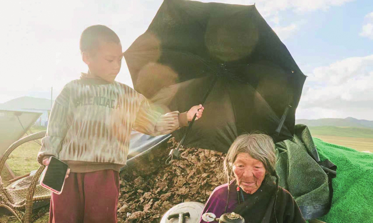 A young nomadic Tibetan shields his great-grandmother from the sun in Northwest China's Qinghai Province, in 2024. Photo: Chellali