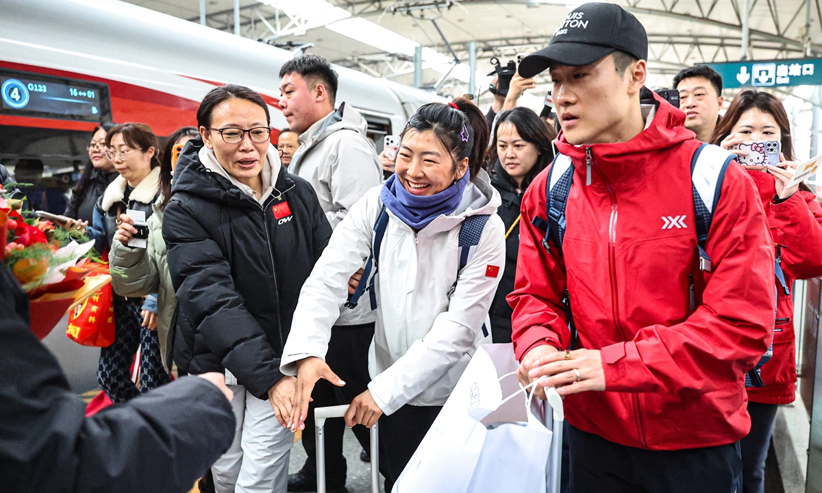 Winter Olympic champions Xu Mengtao (center) and her husband Wang Xindi (right) receive a warm welcome at the railway station after arriving in Shenyang, Northeast China's Liaoning Province, on February 25, 2026. The couple respectively won the men's and women's freestyle skiing aerials gold medals at the Milano Cortina 2026 Olympic Winter Games. Photo: VCG
