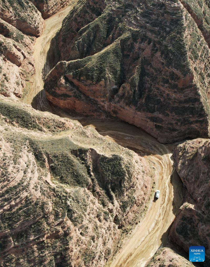 This aerial drone photo taken on April 4, 2026 shows a view of the Shilaquan Canyon in Tangwang Town of Dongxiang Autonomous County, Linxia Hui Autonomous Prefecture, northwest China's Gansu Province. Shilaquan Canyon has an average elevation of approximately 2,000 meters. The red sandstone and gravel layers on both sides of the canyon have been shaped by water erosion and wind abrasion, forming a distinctive Danxia landform. (Xinhua/Chen Bin)