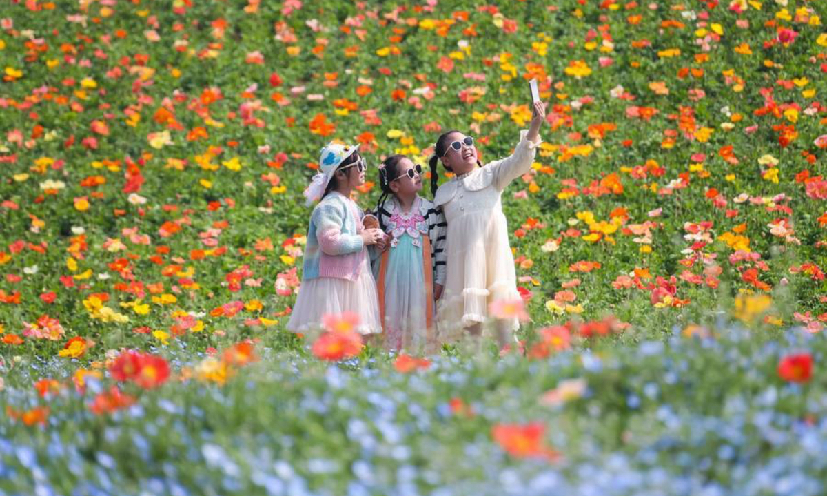Children take selfies at a flower field in Baitu Town of Jurong City, east China's Jiangsu Province, April 2, 2026. (Photo by Zhong Xueman/Xinhua)