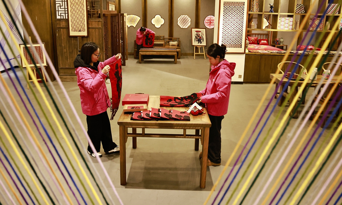 Workers arrange brocade products on shelves for sale at a Tujia brocade production and research base in Zhangjiajie, Hunan Province, on February 24, 2026.