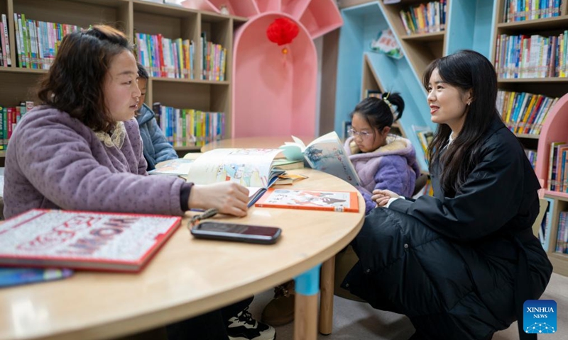 Zhang Qiongli (1st R) talks with a parent at a library in Enshi Tujia and Miao Autonomous Prefecture, central China's Hubei Province, Feb. 4, 2026. Photo: Xinhua