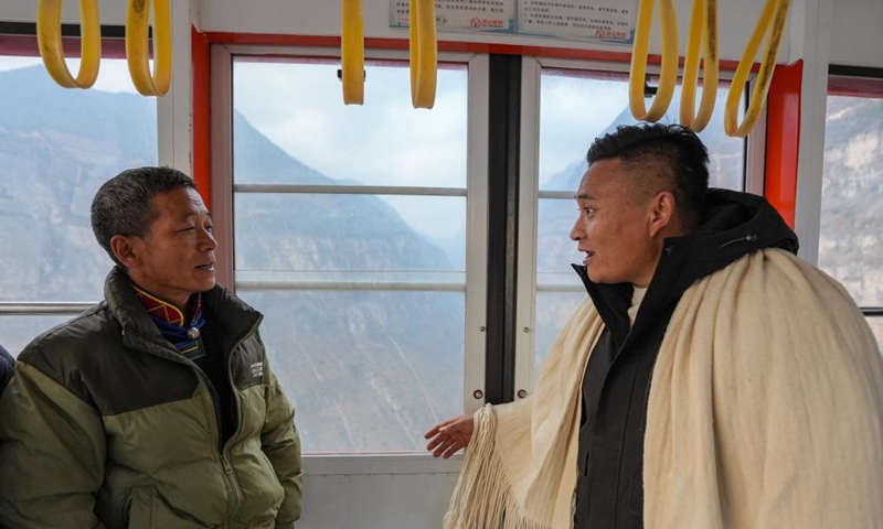 Zheng Wangchun (R) talks with a migrant worker returning home inside a cable car in Gulu Village of Hanyuan County, southwest China's Sichuan Province, Jan. 28, 2026. Photo: Xinhua