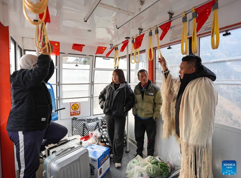 Zheng Wangchun (1st R) talks with migrant workers returning home inside a cable car in Gulu Village of Hanyuan County, southwest China's Sichuan Province, Jan. 28, 2026. Photo: Xinhua