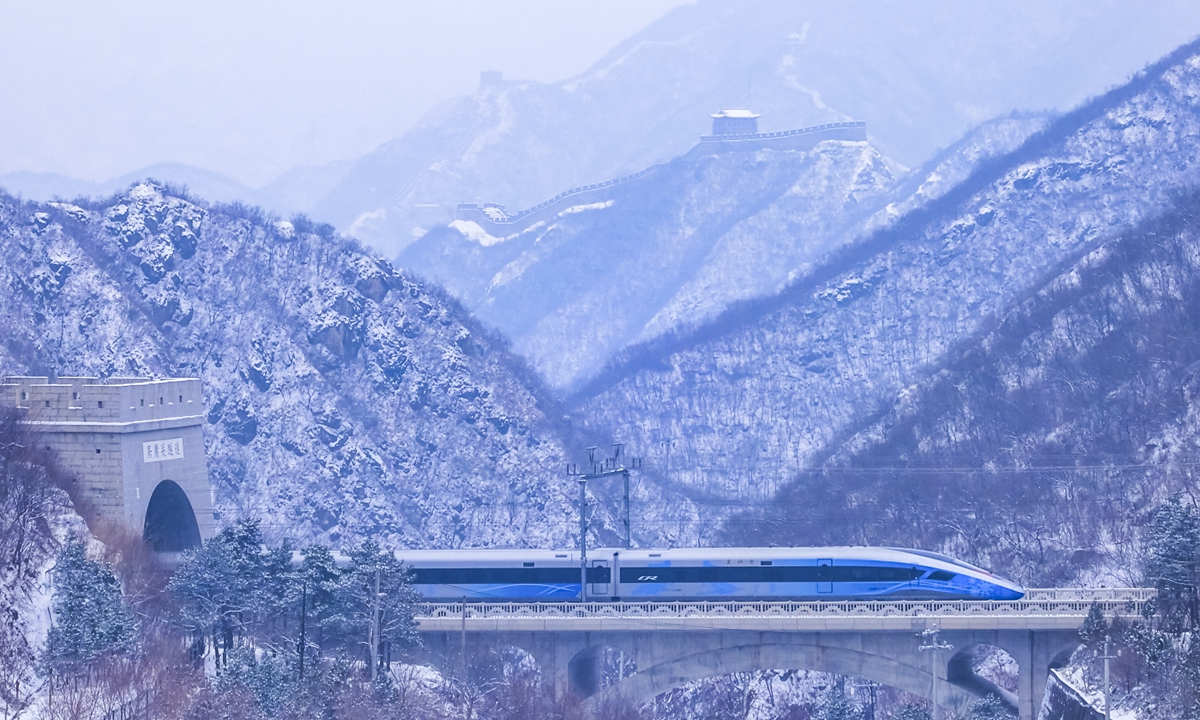 A high-speed train emerges from a tunnel at the Juyongguan Pass in Beijing on March 5, 2026, as the mountains and the Great Wall are covered in snow. The Beijing-Tianjin-Hebei region now boasts a high-speed rail network of 2,675 kilometers, covering all cities at or above the prefecture level within the area. Photo: VCG