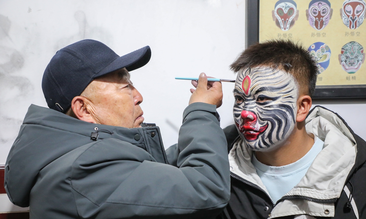A makeup artist applies makeup to 16-year-old Shehuo performer (right) in Huangzhong district, Xining, Northwest China's Qinghai Province, on February 28, 2026. Photo: VCG