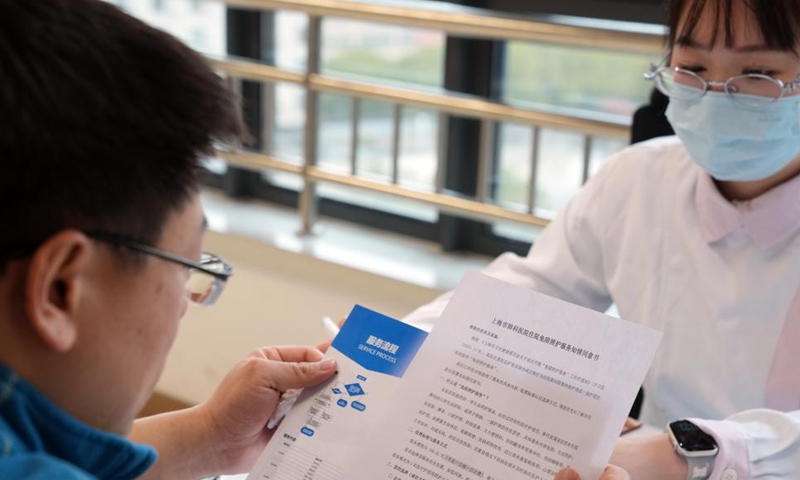 A family member of an inpatient learns about the companion-free care services at a hospital in Shanghai, east China, Feb. 26, 2026.(Xinhua/Liu Ying)