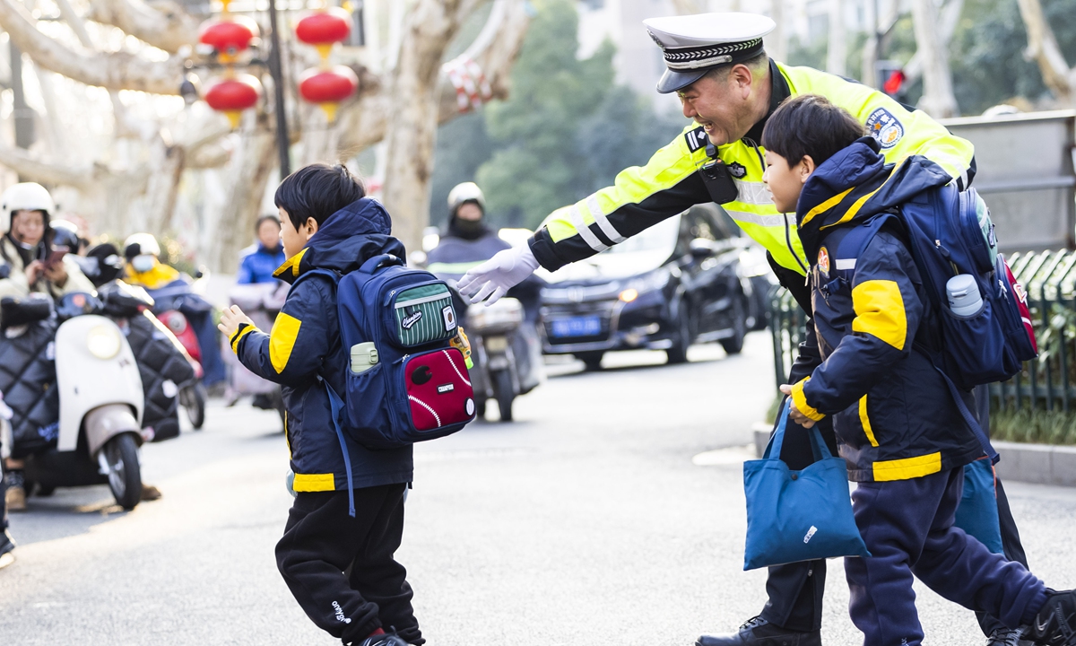 A police officer escorts primary school students returning to school at the entrance of a primary school in Nanjing, East China's Jiangsu Province, on February 13, 2025. Photo: VCG