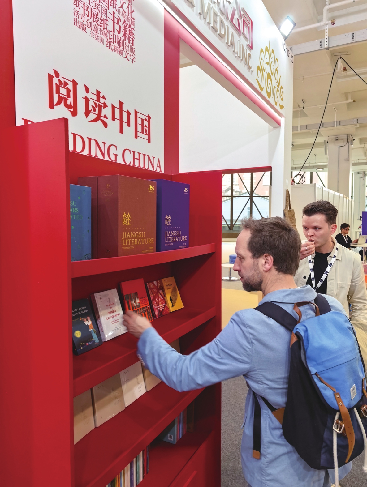 A reader picks up a Chinese book in English edition at the 2026 London Book Fair. Photo: Courtesy of the Phoenix Publishing and Media Group