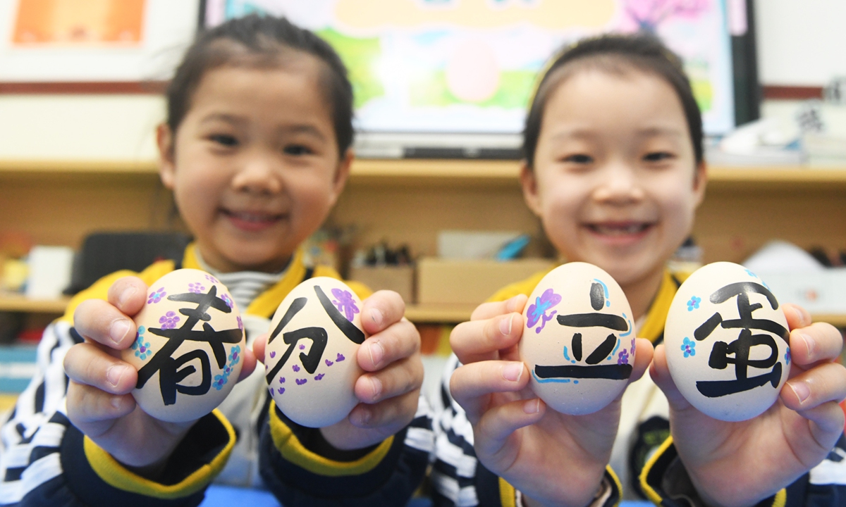 Two children at the Third Municipal Kindergarten in Xinle, Shijiazhuang, North China's Hebei Province, show their hand-painted colored eggs featuring the Chinese words 