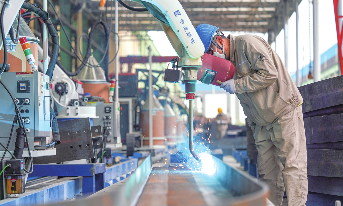 A worker inspects welding points as robots produce steel structures at China Construction Steel Structure Sichuan Co in Meishan, Southwest China's Sichuan Province, on March 23, 2026. Guided by digital transformation, the region has actively supported enterprises in upgrading production technologies and equipment. Photo: VCG
