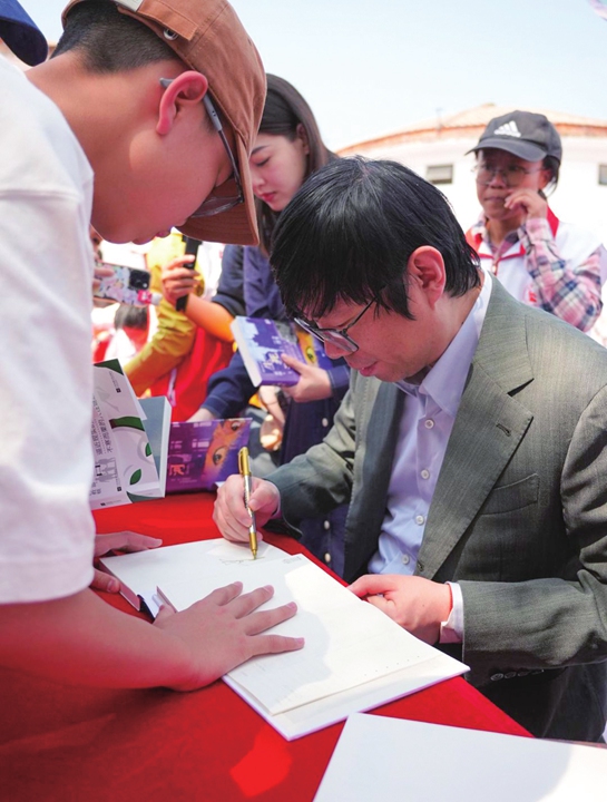Writer Cai Jun signs books for readers. Photo: Courtesy of the China Writers Association