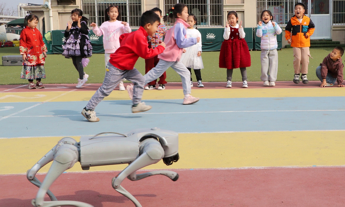 Children race against a robot dog in a kindergarten in Dongying, East China's Shandong Province, on March 24, 2026. The kindergarten held a popular science activity, allowing children to experience the charm of science and technology, and stimulating their awareness of innovation and creativity. Photo: VCG